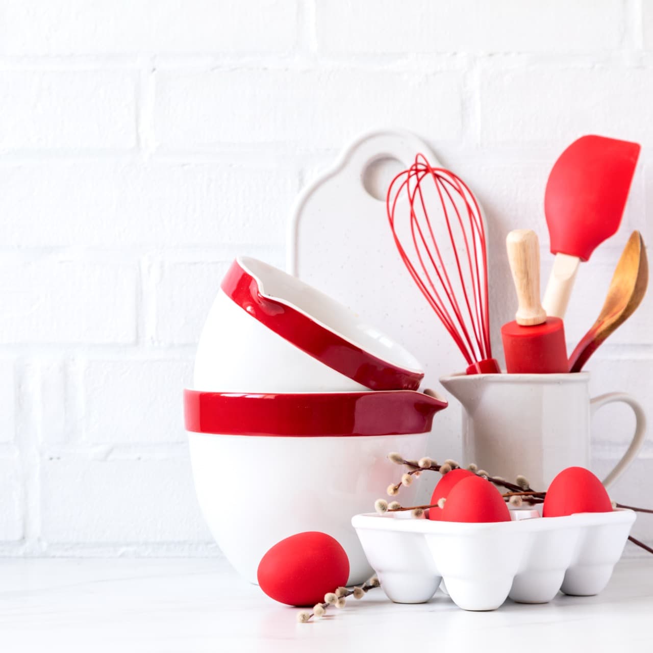 Easter Background for baking with ingredients for cooking. Traditional Easter decoration eggs and rabbit.Kitchen utensils,tools color red and dishware on on the background white  brick wall.Blank space for a text, front view