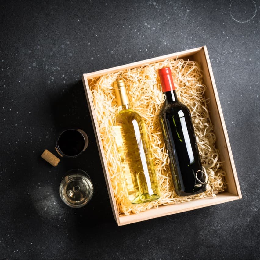 Red and white wine in wooden box at black background. Top view with copy space.