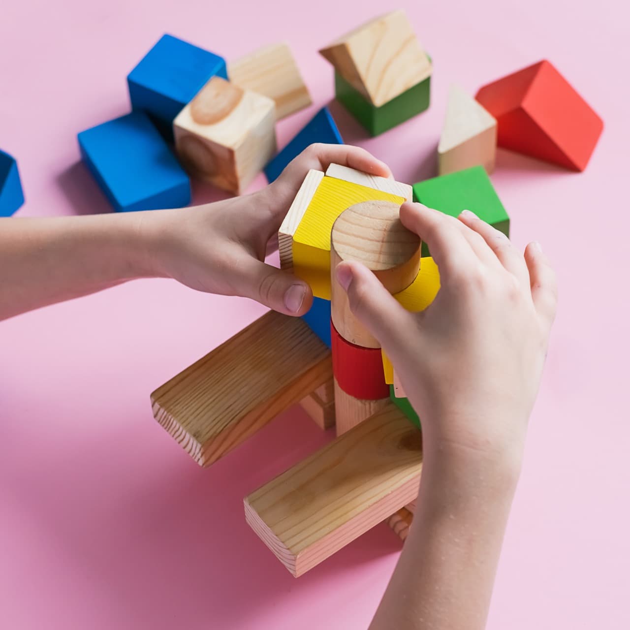 Little kid plays assemble with wooden cubes constructor. Education concept for children learning. Children's toys from environmentally friendly materials.