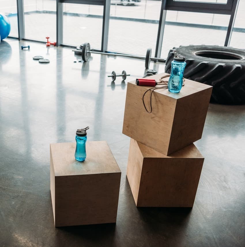 jump rope and bottles of water on wooden boxes, dumbbells, barbell, training tire, fitness balls,